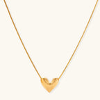 Dainty 18K gold-plated sterling silver necklace with small heart pendant on delicate chain against cream background.