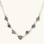 Adjustable cream cord necklace with white spotted stone beads featuring black speckles on neutral background