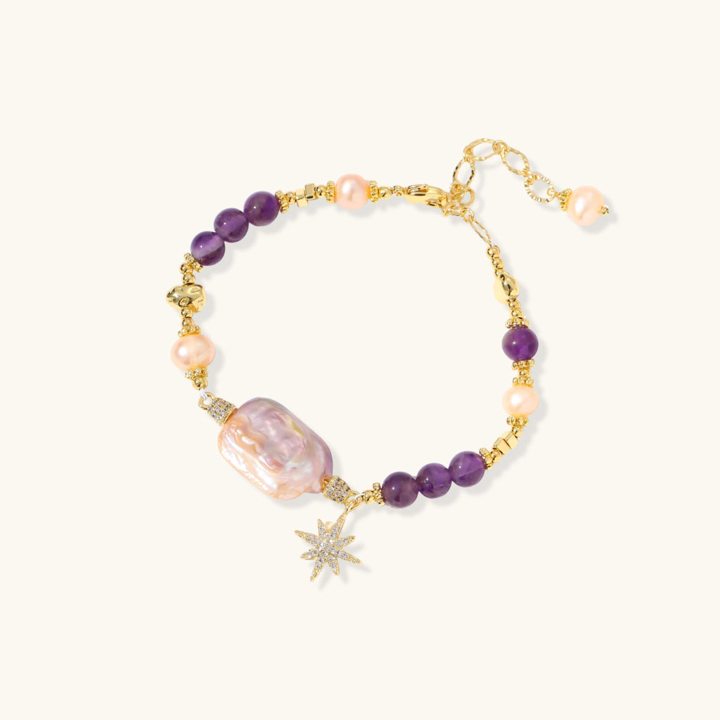 Gold-plated bracelet with baroque pearl centerpiece, amethyst beads, and crystal star charm on white background.