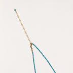 Delicate gold vermeil necklace with teal apatite beads and freshwater pearl on white background.