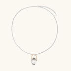 Whimsical owl pendant holding a white pearl on a gold swing, rhodium-plated silver chain on cream background.