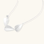 Minimalist sterling silver necklace with three brushed leaf-shaped pendants on delicate chain against white background