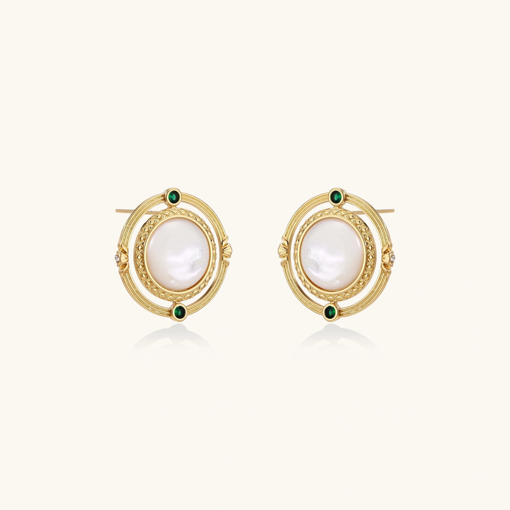 Circular gold stud earrings with iridescent mother-of-pearl center and green zirconia accents on cream background.