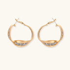 Sculptural wavy hoop earrings with crystal details and organic curved silhouette in gold and silver variants