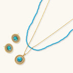 Gold-plated turquoise jewelry set with circular medallion pendant, beaded necklace, and matching stud earrings on white background