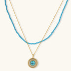 Gold-plated turquoise jewelry set with circular medallion pendant, beaded necklace, and matching stud earrings on white background