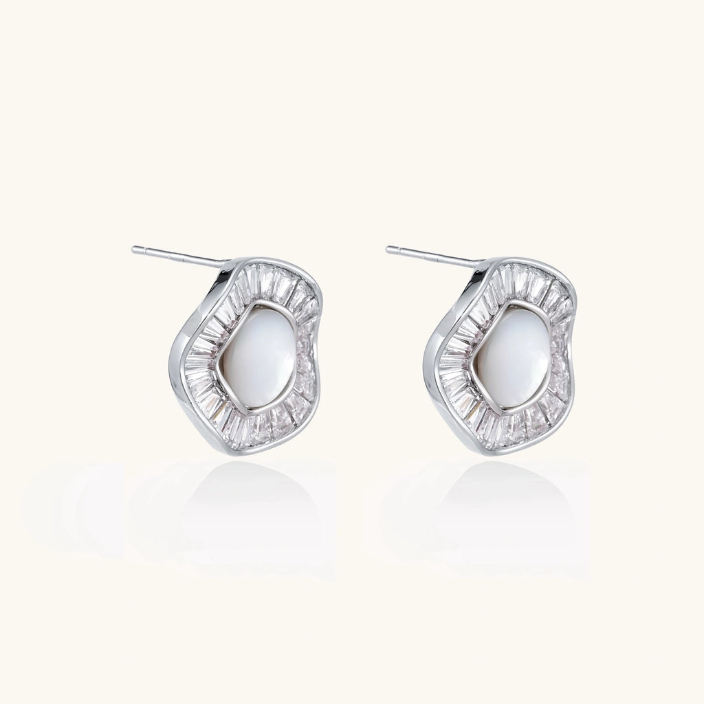 White gold-plated stud earrings with iridescent pearl centers surrounded by baguette crystal halos on white background.