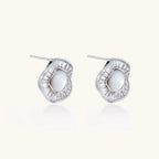 White gold-plated stud earrings with iridescent pearl centers surrounded by baguette crystal halos on white background.