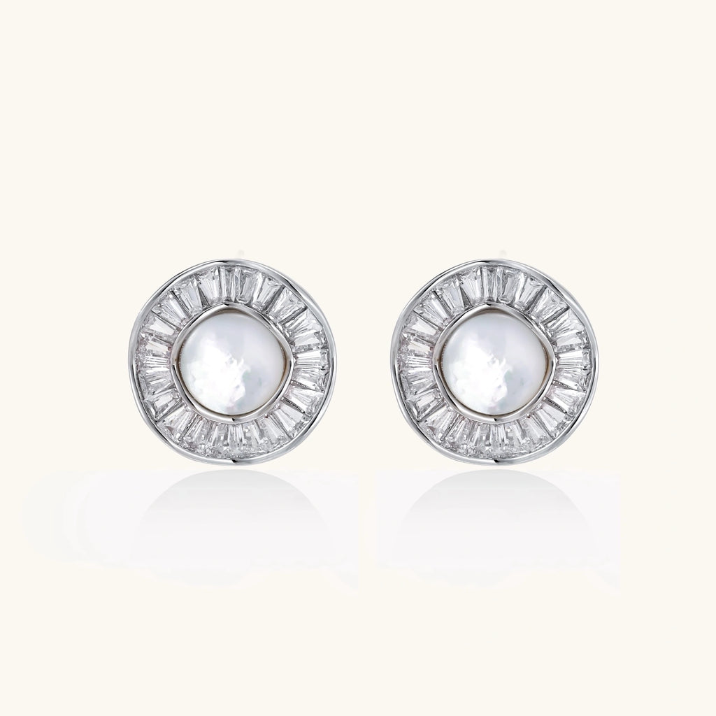 White gold-plated stud earrings with iridescent pearl centers surrounded by baguette crystal halos on white background.