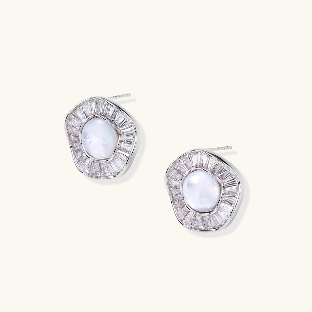 White gold-plated stud earrings with iridescent pearl centers surrounded by baguette crystal halos on white background.