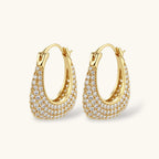 Gold-plated hoop earrings fully covered in sparkling zircon crystals with hinged closure on neutral background