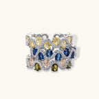 Adjustable ring with blue cubic zirconia stones in flowing wave pattern, copper with platinum plating on white background.