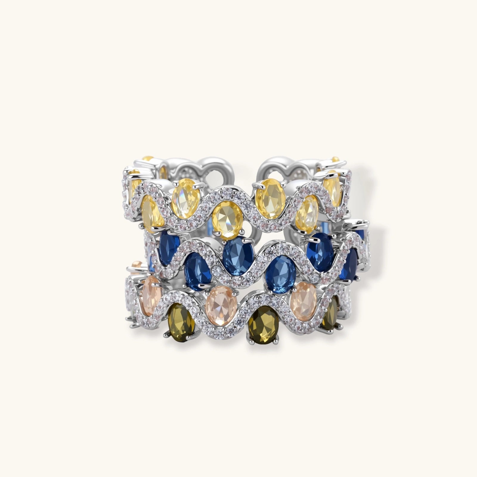 Adjustable ring with blue cubic zirconia stones in flowing wave pattern, copper with platinum plating on white background.