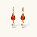 Gold-plated drop earrings featuring amber teardrops and white baroque pearls on light background.