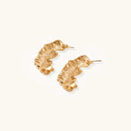 Sculptural gold hoops with textured wave patterns and rippled surface in 14K plating, shown from front and back angles